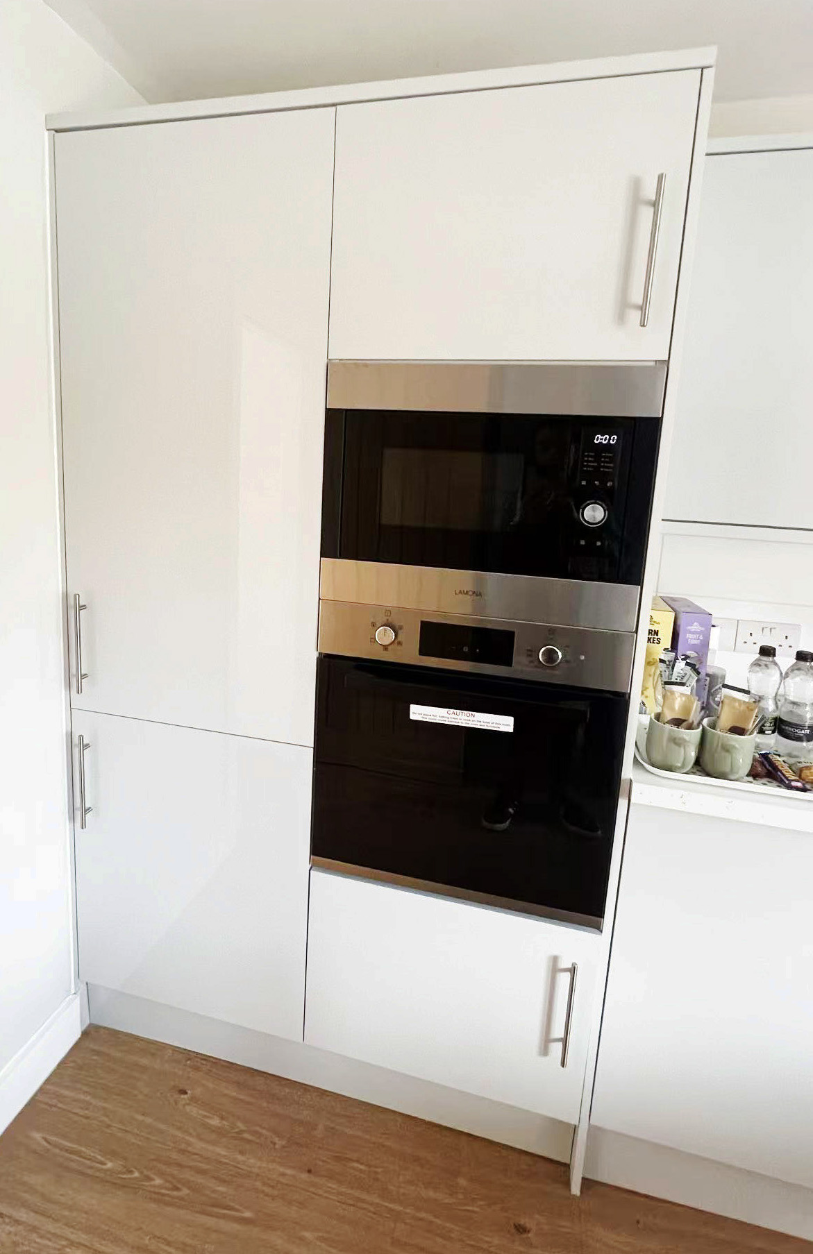 Built-in microwave above an electric oven set in white cabinetry in a modern kitchen.